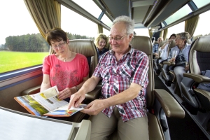 Passagiere sitzen im First Class Bus mit viel Bewegungsfreiheit in der 2+1er Bestuhlung