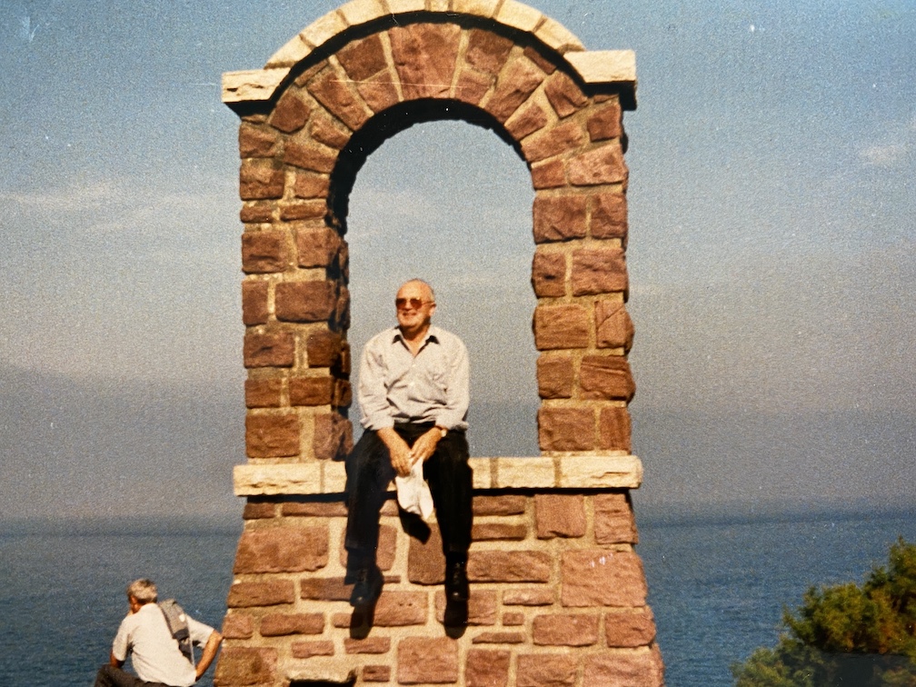 Mann auf Mauer mit Torbogen am Meer