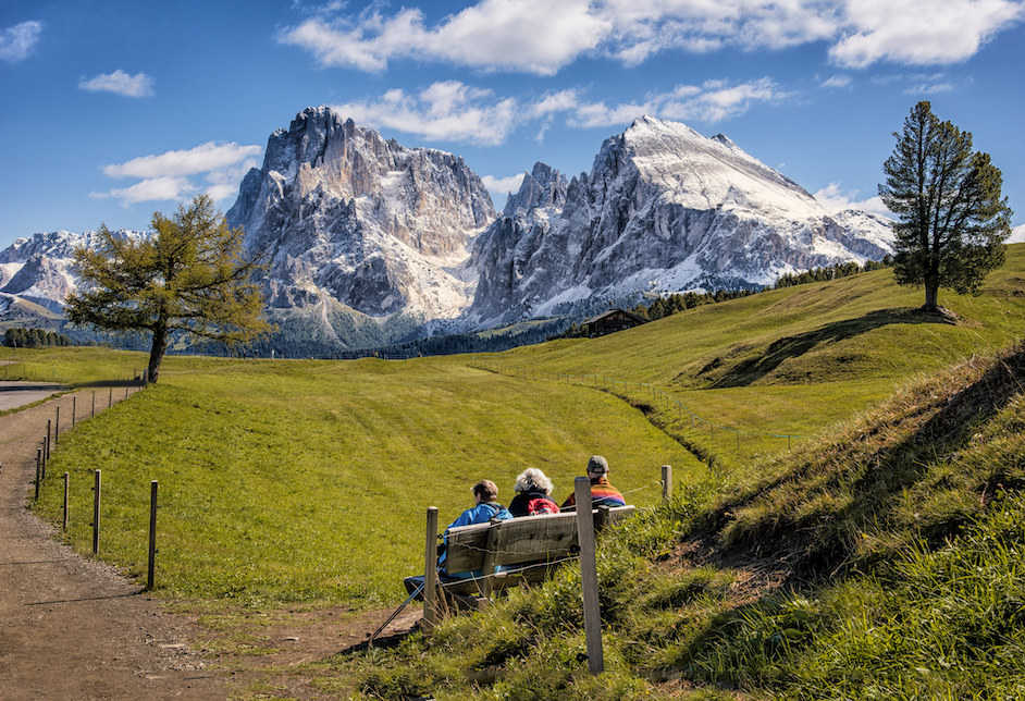 Senioren sitzen auf einer Bank vor einem Bergpanorama