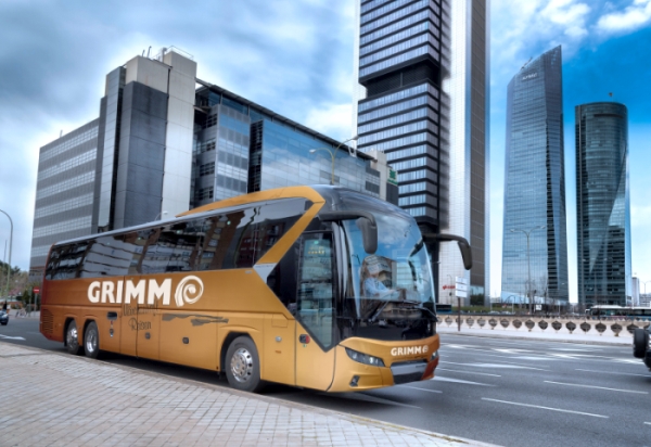 First Class Bus vor einer Skyline auf einer großen Straße