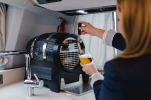 Servicekraft zapft im First-Class-Bus in der Bordküche Bier