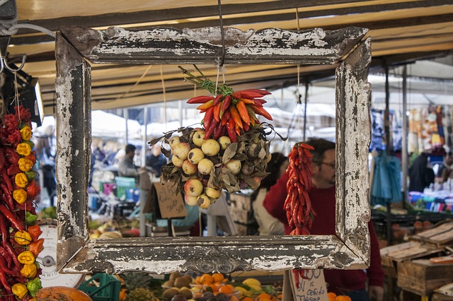 drapiertes getroknetes Gemüse hängt im Strauß in einem alten Bilderrahmen auf einem Markt