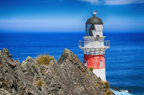 Leuchtturm an einer Klippe vor blauem Meer
