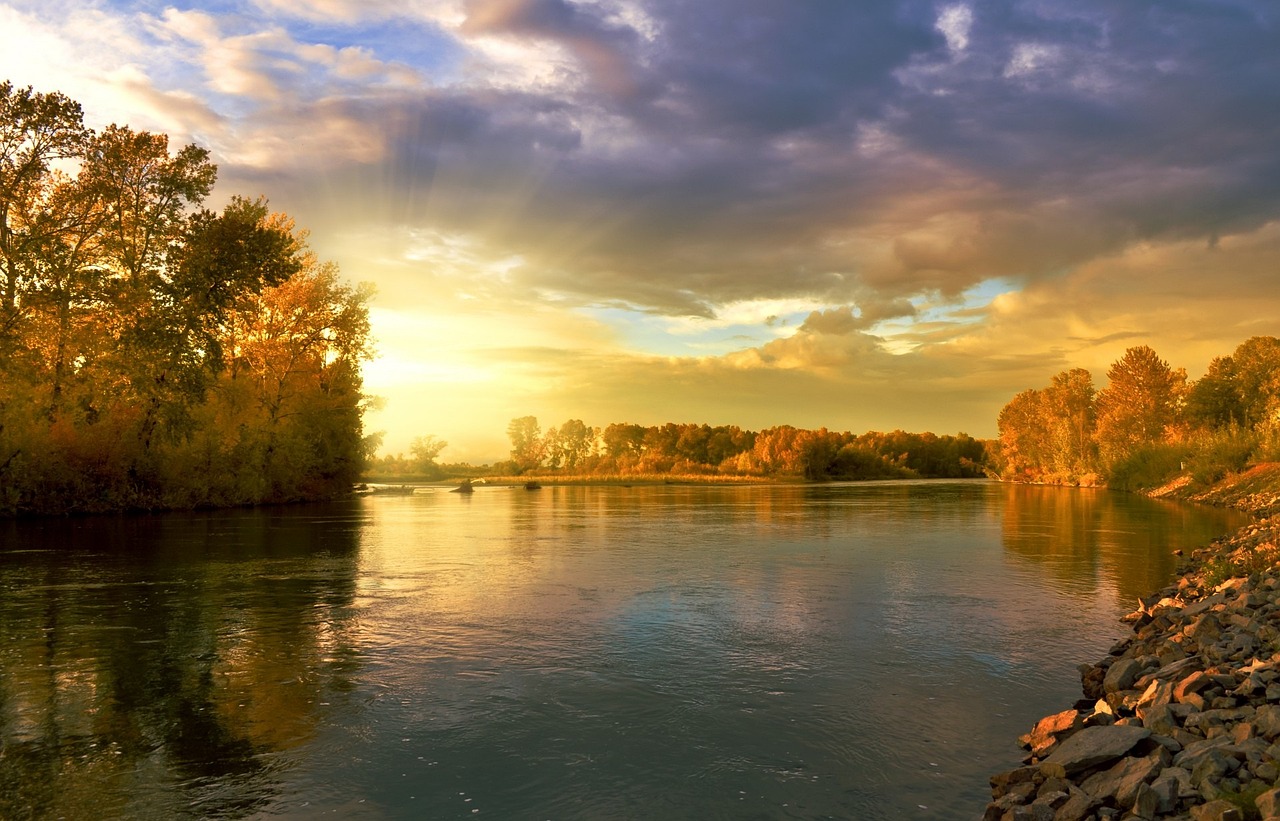 Ruhiger Fluss in der Abenddämmerung mit bewaldetem Ufer