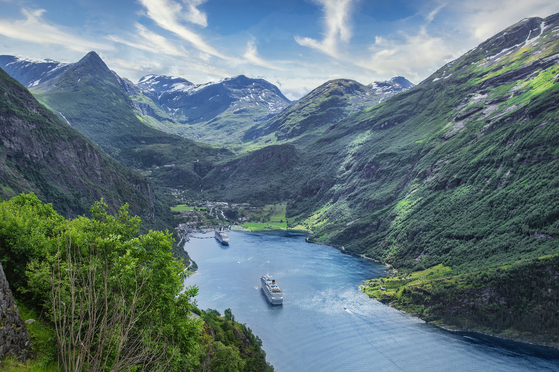 Zwei Flusskreuzfahrtschiffe fahren in einen Hafen am Ende eines Fjordes mit sehr hohen Bergen