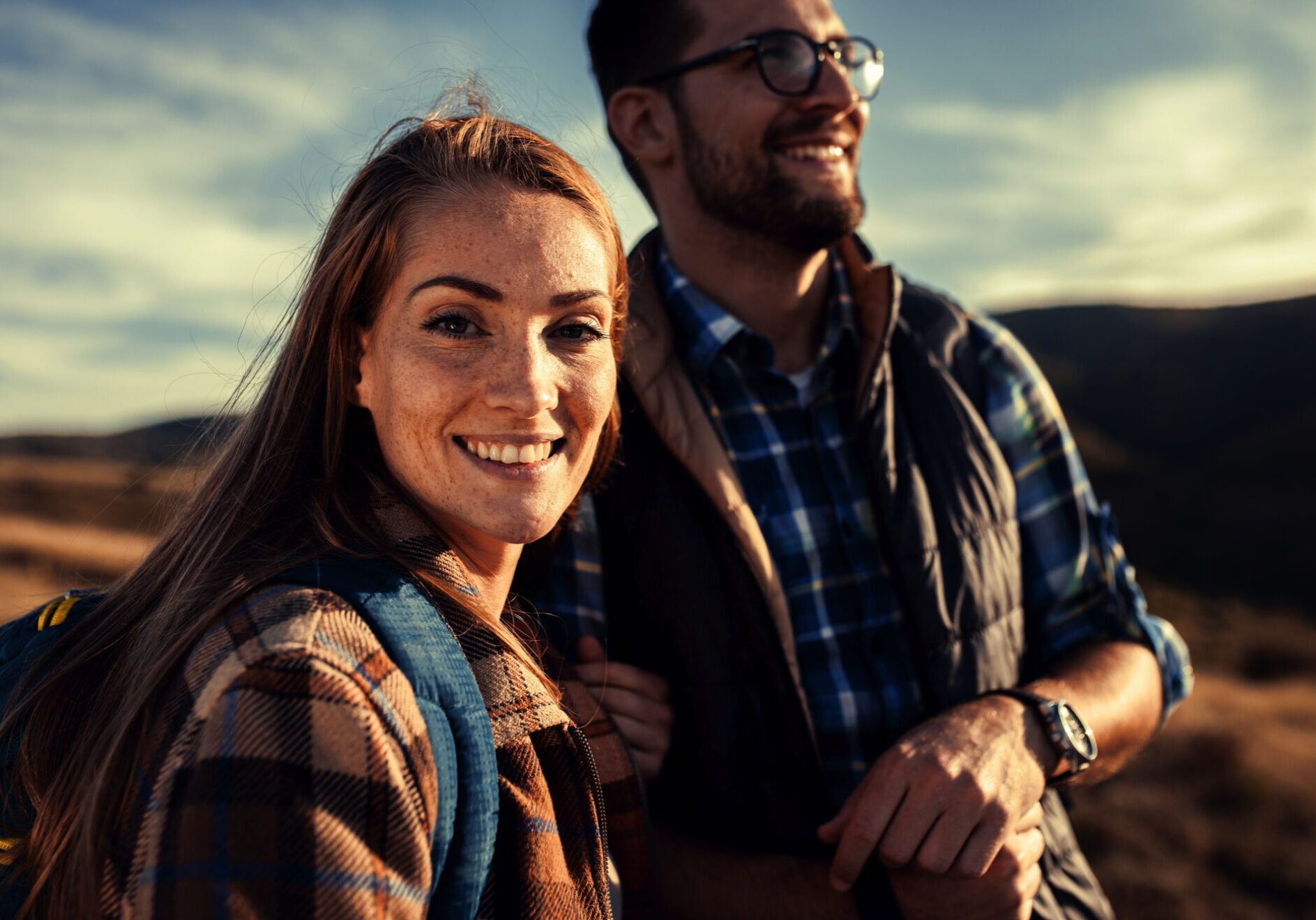 Zwei Personen lächeln beim Wandern und genießen die warmen Sonnenstrahlen