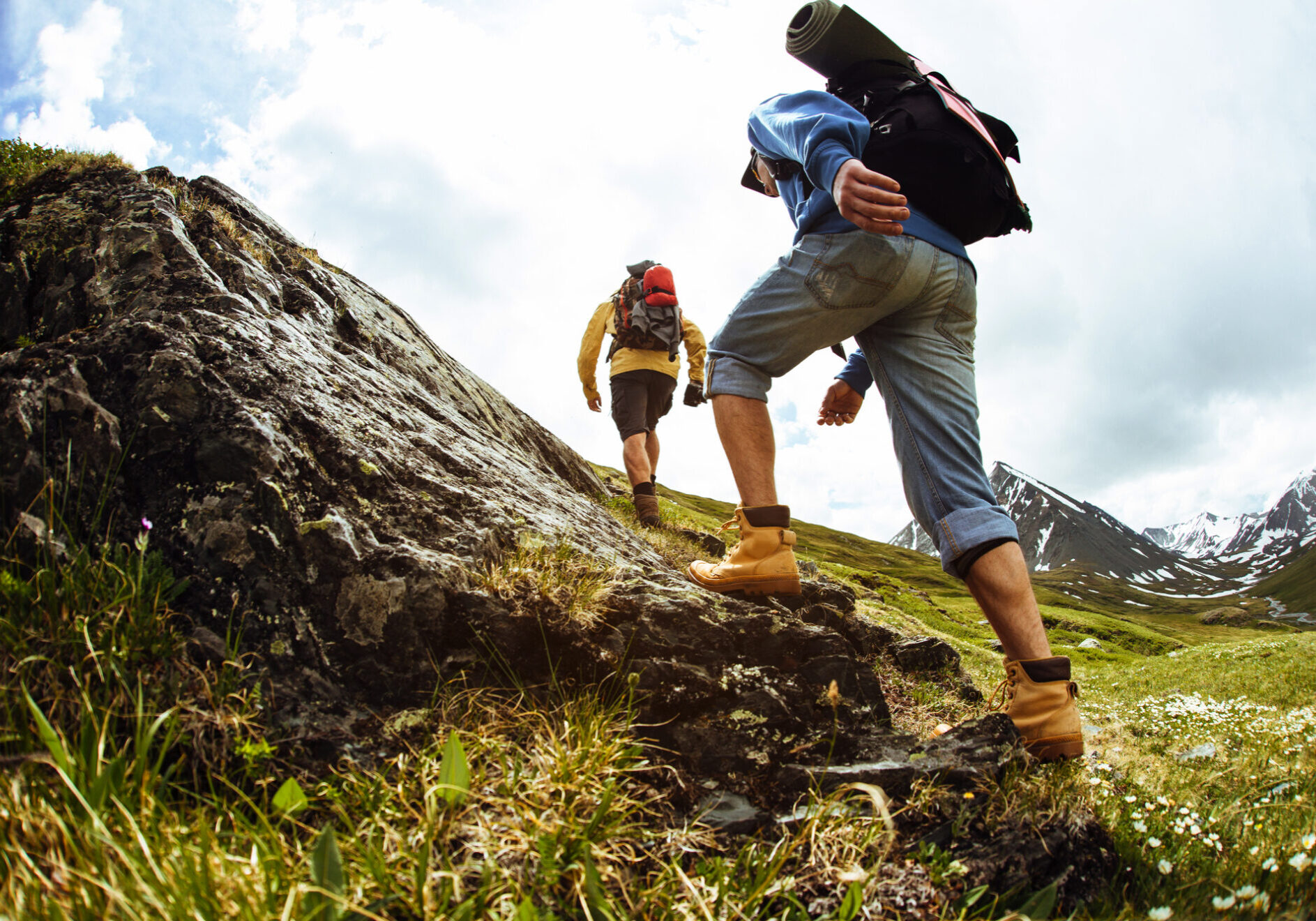 Zwei Personen in Wanderkleidung steigen einen flachen Steinhügel hinauf